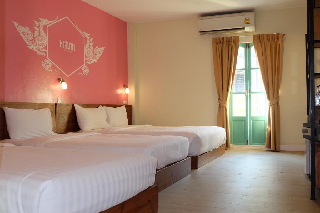 曼谷Siri Poshtel Bangkok的红色墙壁的酒店客房内的两张床
