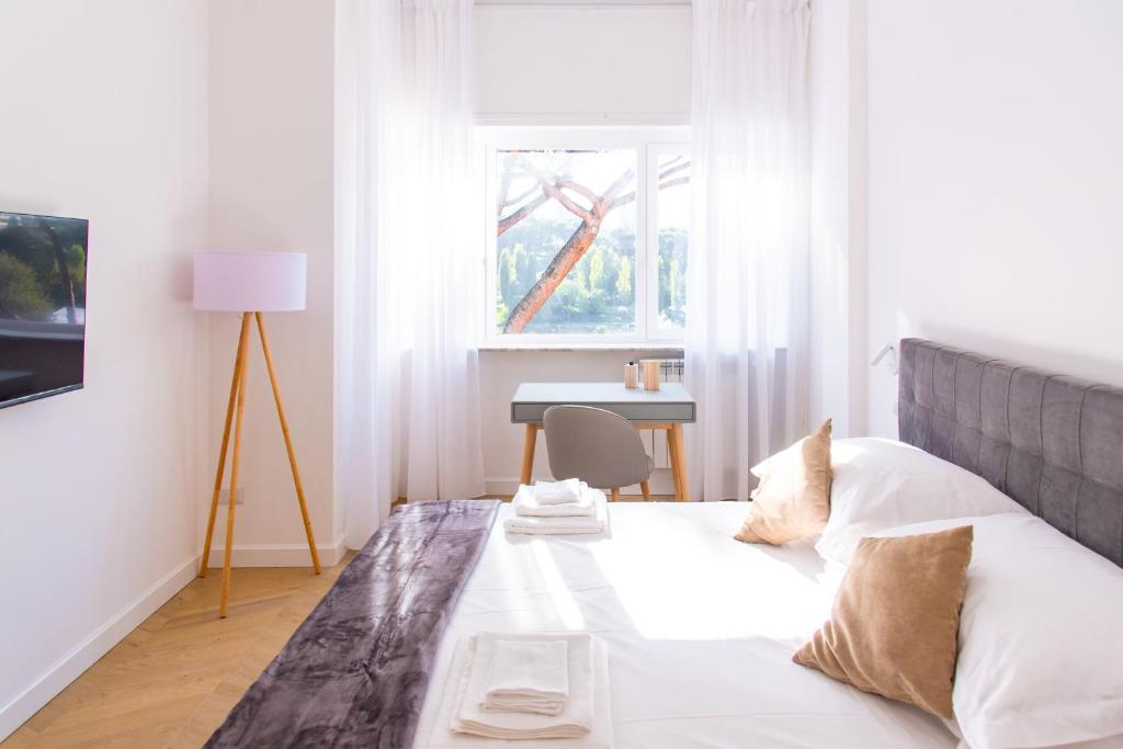 罗马Eur terrazzo vista Laghetto Modigliani的一间卧室配有一张带桌子和窗户的床
