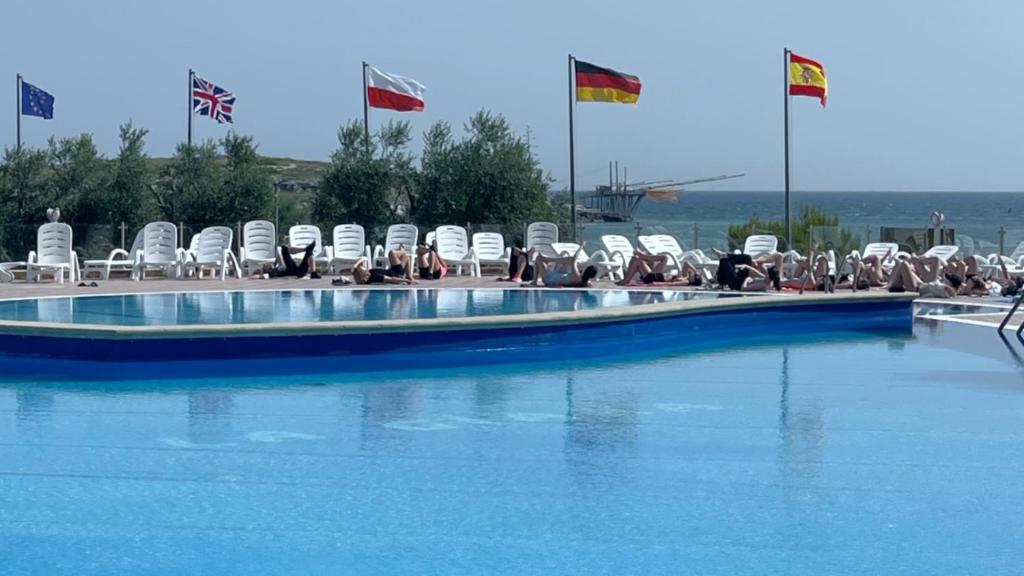 维耶斯泰拉吉尔拉村酒店的一群人坐在游泳池边的椅子上