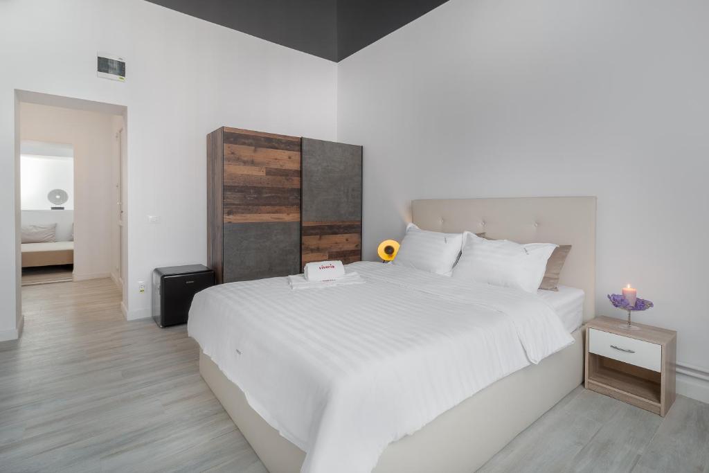 奥拉迪亚VIVERIA的卧室配有一张白色大床和木制床头板