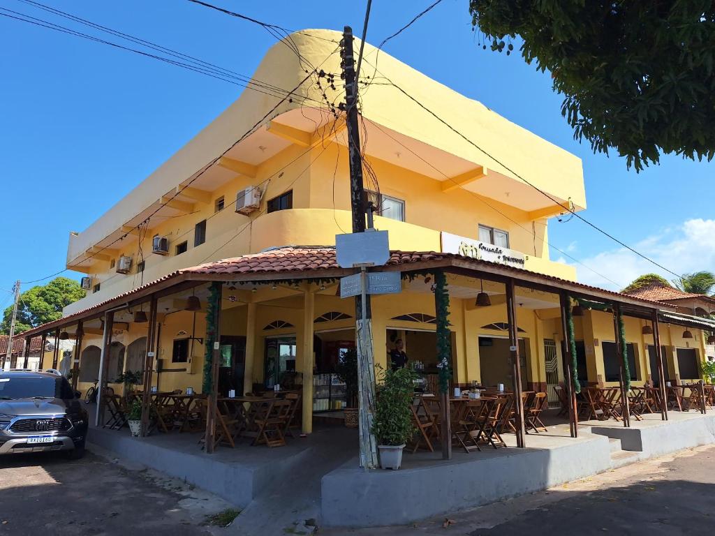 索雷HOTEL E RESTAURANTE ILHA BELA的前面设有桌椅的黄色建筑