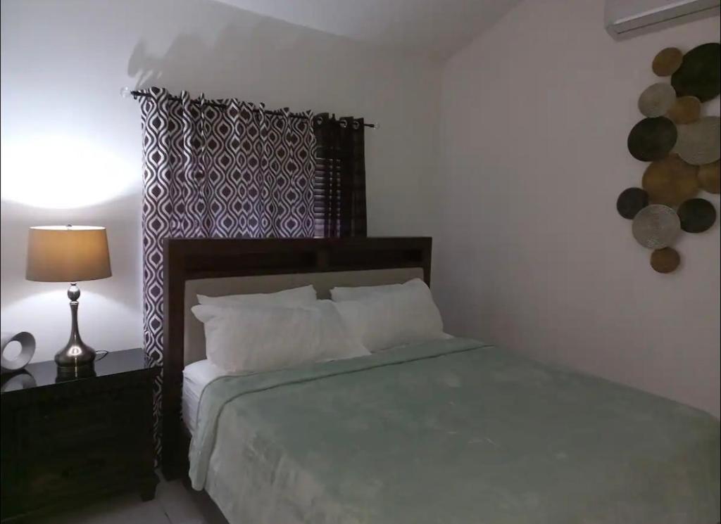 波特莫尔Mi Casa Comfort Estate的一间卧室配有一张床和一张带台灯的桌子