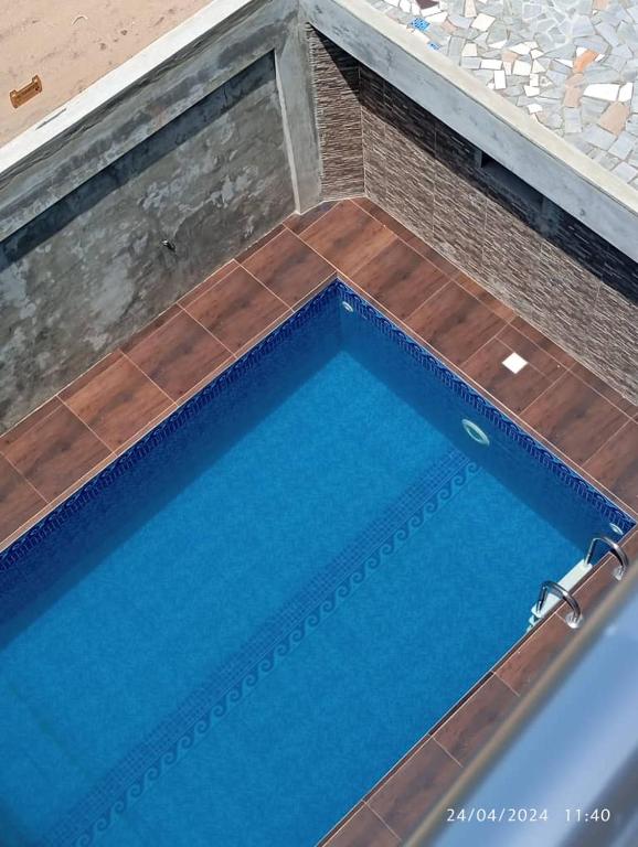 科托努Luxe Villa的蓝色海水和木地板的大型游泳池