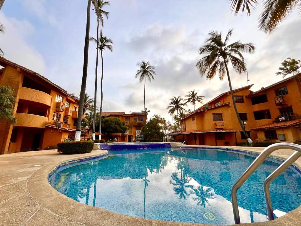 TucacasUn Oasis entre Olas y Palmeras con Playa Privada的一座棕榈树和建筑的大型游泳池