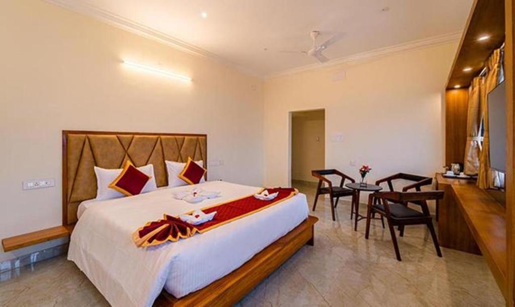 蓬蒂切里FabHotel Prime AR Phalazzo Resort的一间卧室配有一张大床和一张桌子