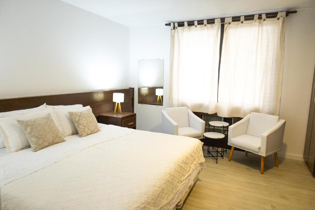 圣保罗Edifício Flat Hotel Congonhas的一间卧室配有一张大床和两把椅子