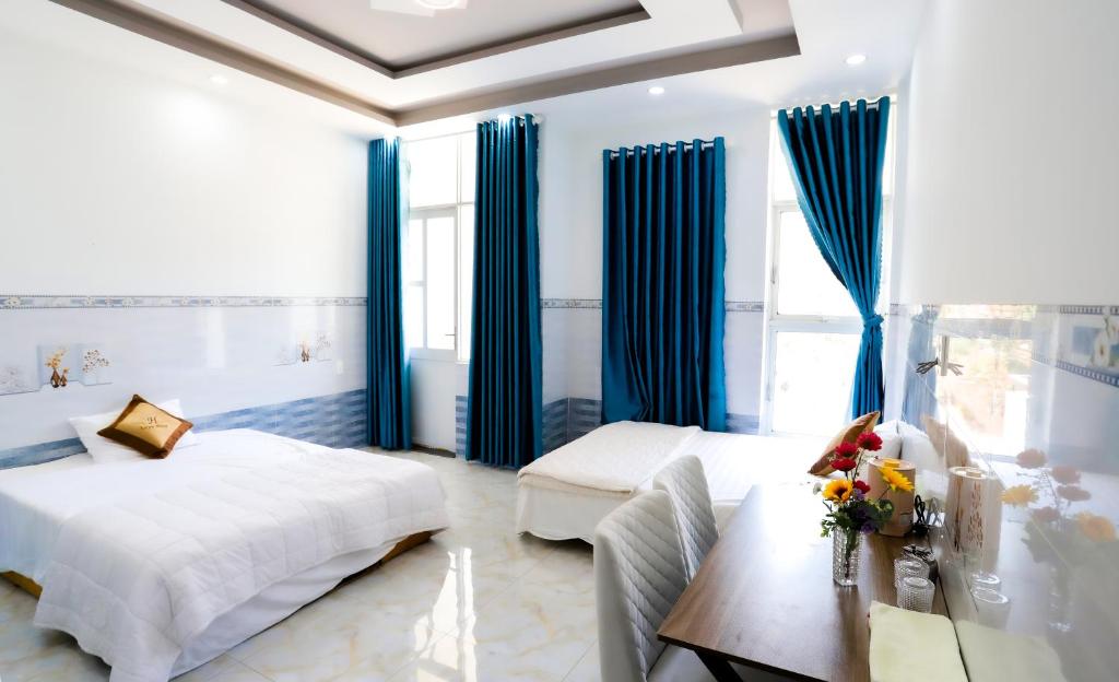Nhơn TrạchHotel Trâm Anh的一间卧室配有蓝色窗帘、一张床和一张书桌