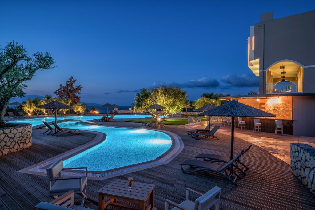 查加基恩Elegance Luxury Executive Suites - Adults Only的游泳池在晚上提供椅子和遮阳伞