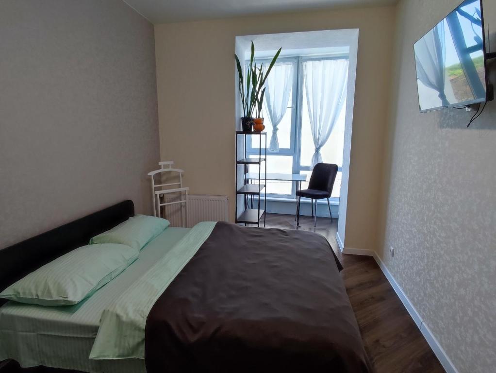 赫梅利尼茨基Апартаменти в центрі Хмельницького (біля ТРЦ ЛибідьПлаза)的一间卧室配有一张床、一张桌子和一个窗户。