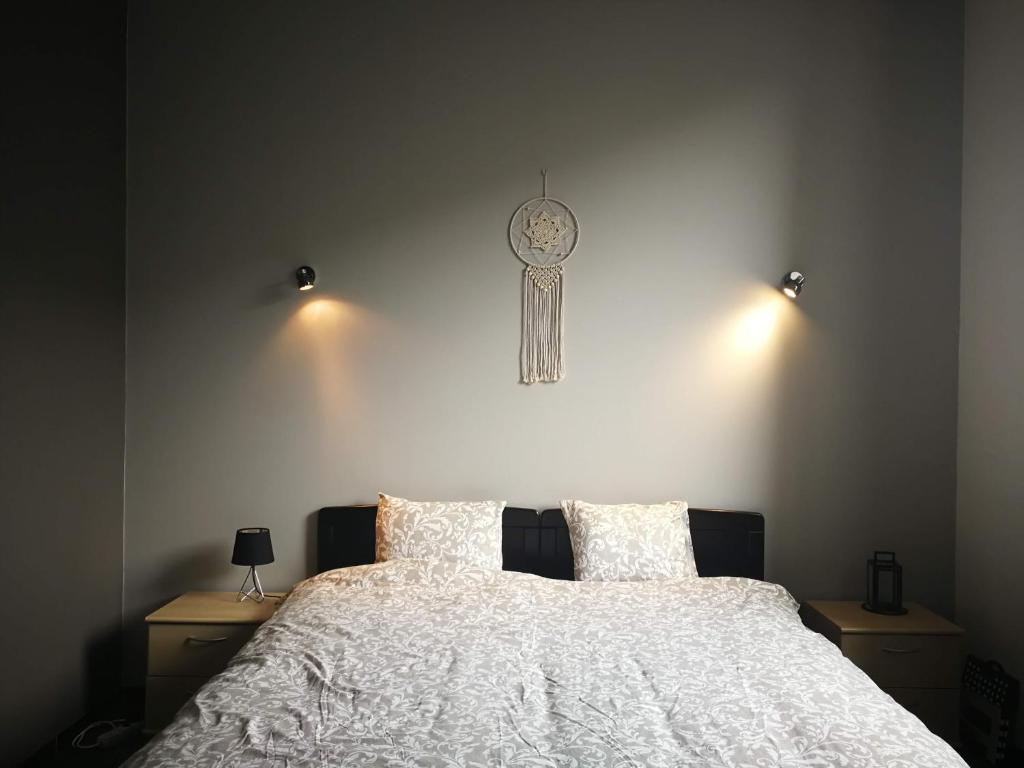 AndenneMégi des Aguesses的卧室配有一张挂在墙上的带时钟的床