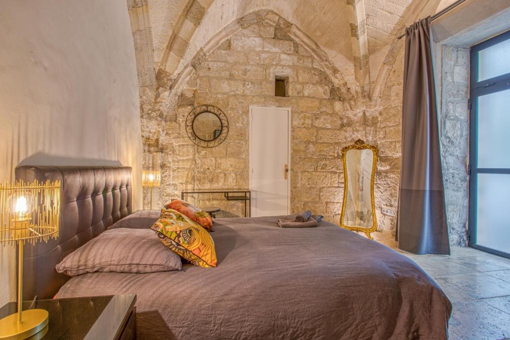 阿维尼翁La Chapelle du Miracle的卧室配有一张石墙内的大床