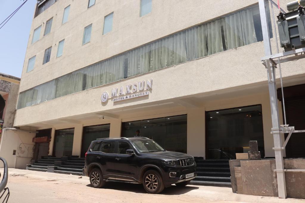 瓜廖尔Hotel maxsun gwalior的停在大楼前的一辆黑色汽车