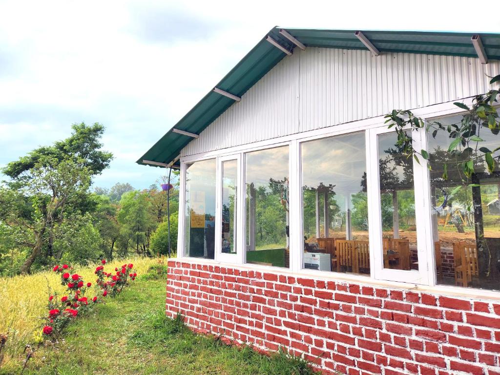 比尔瓦Hipostel Bir - Stay and Cafe的草上带窗户和鲜花的砖砌建筑