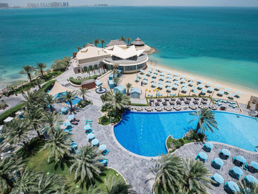 多哈多哈希尔顿酒店的享有带游泳池和海洋的度假村的空中景致