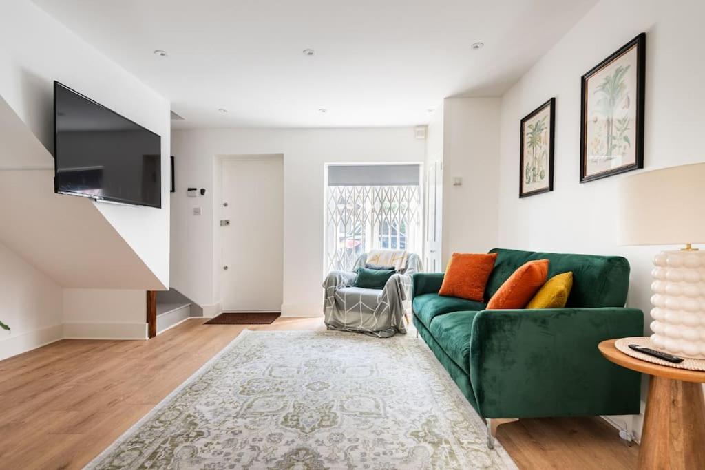 伦敦2BD Mews House, Wanstead的客厅配有绿色沙发和电视