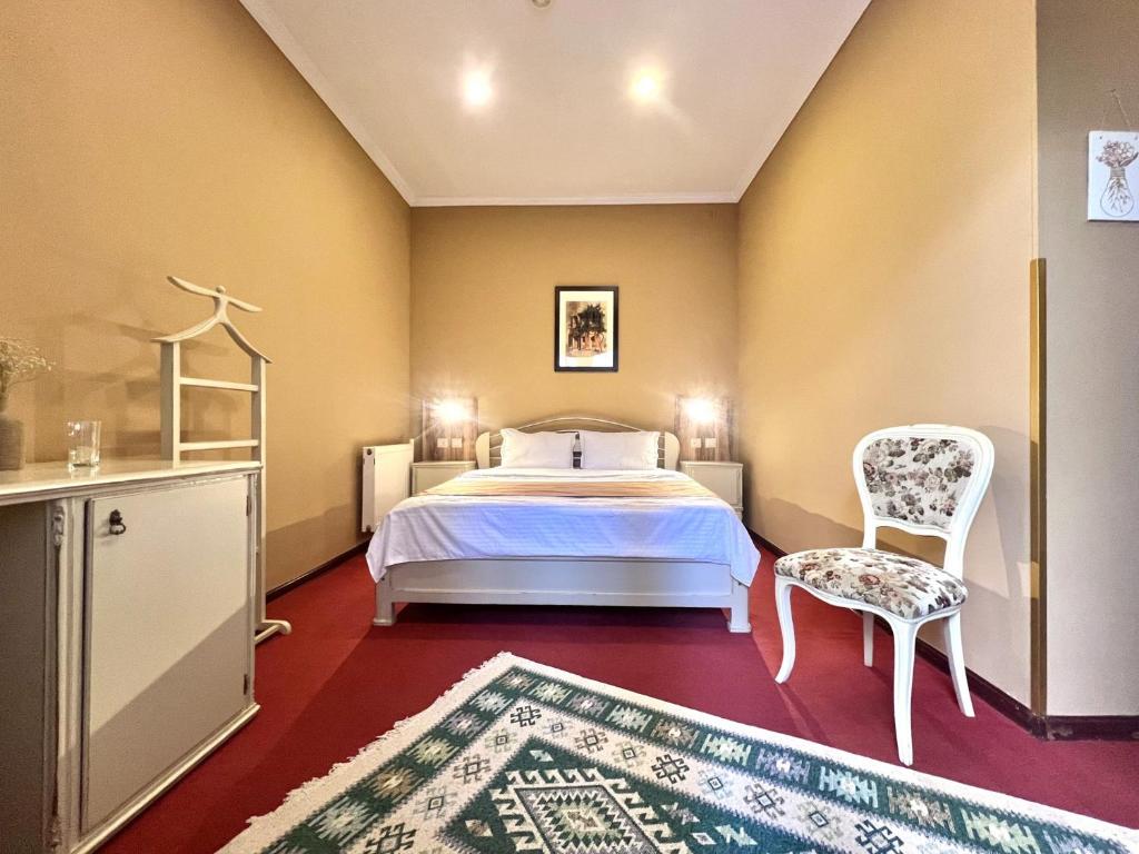 第比利斯Madera Hotel的一间卧室配有一张床、一把椅子和地毯