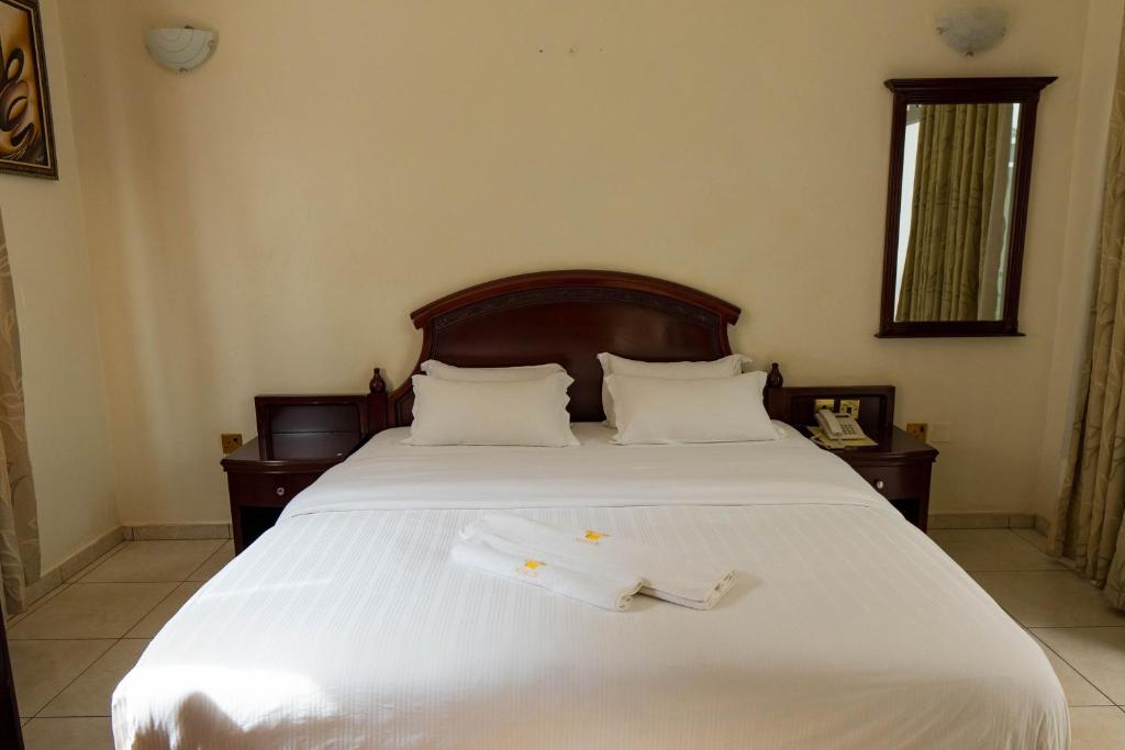 基加利Nobilis Hotel and Apartments的一间卧室配有一张带两条白色毛巾的床