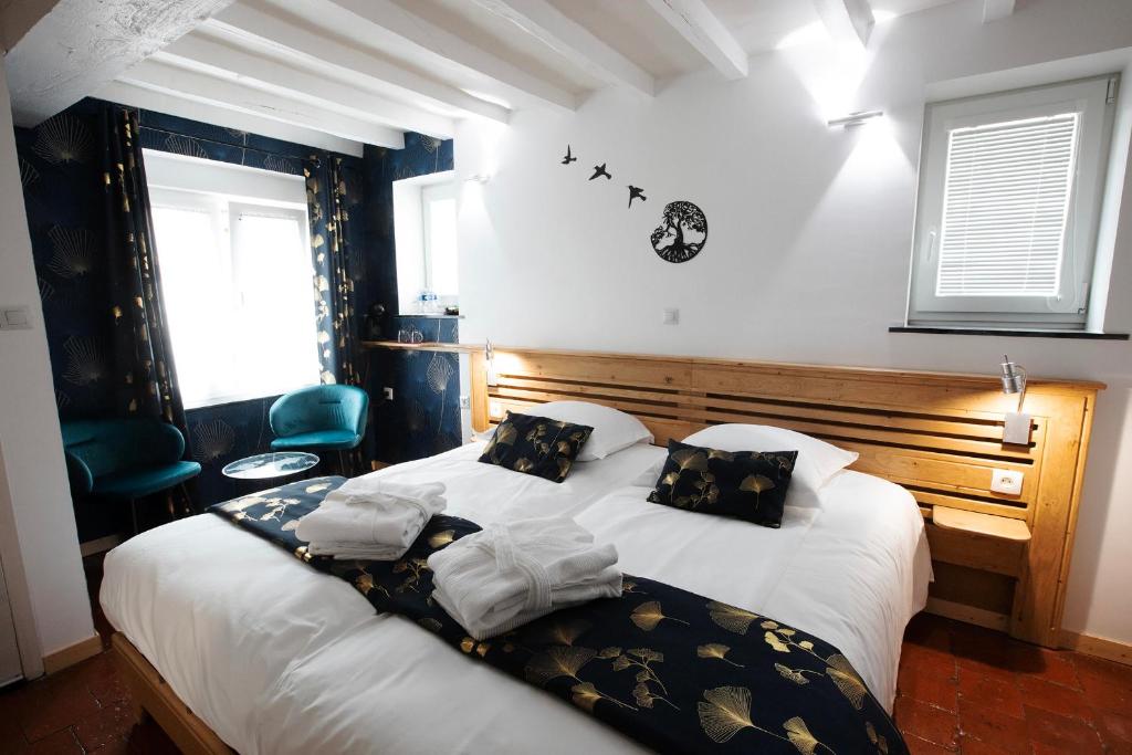 GommegniesAu repos de la licorne的一间卧室配有带白色床单和黑色枕头的床。