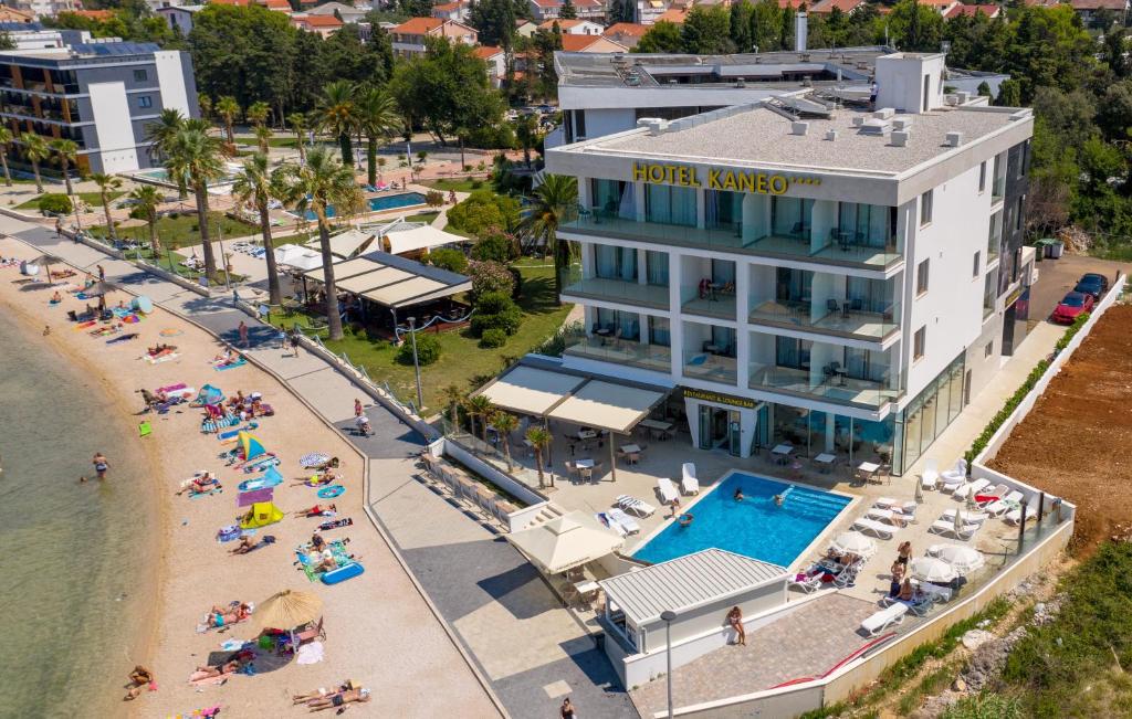 诺瓦利娅Kaneo beach hotel Novalja的海滩上与人们一起的酒店空中景观