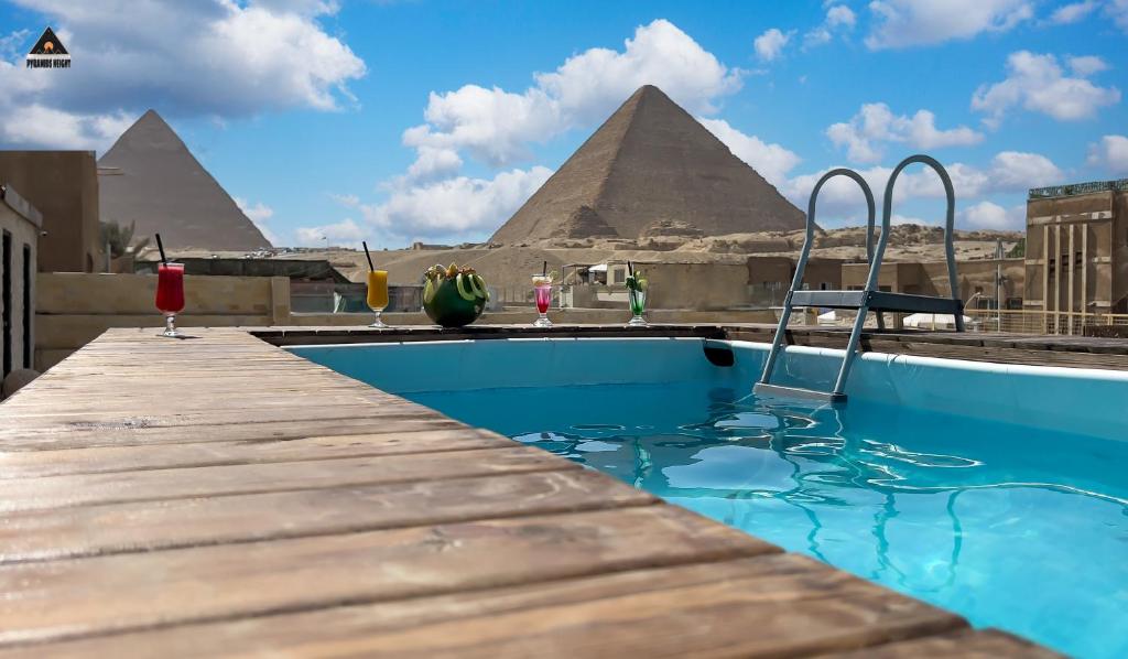开罗Pyramids Height Hotel & Pyramids Master Scene Rooftop的一座有金字塔背景的游泳池