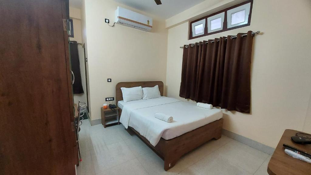 古瓦哈提Hotel Hari Gayatri Regent的一间卧室配有一张带白色床单的床和一扇窗户。