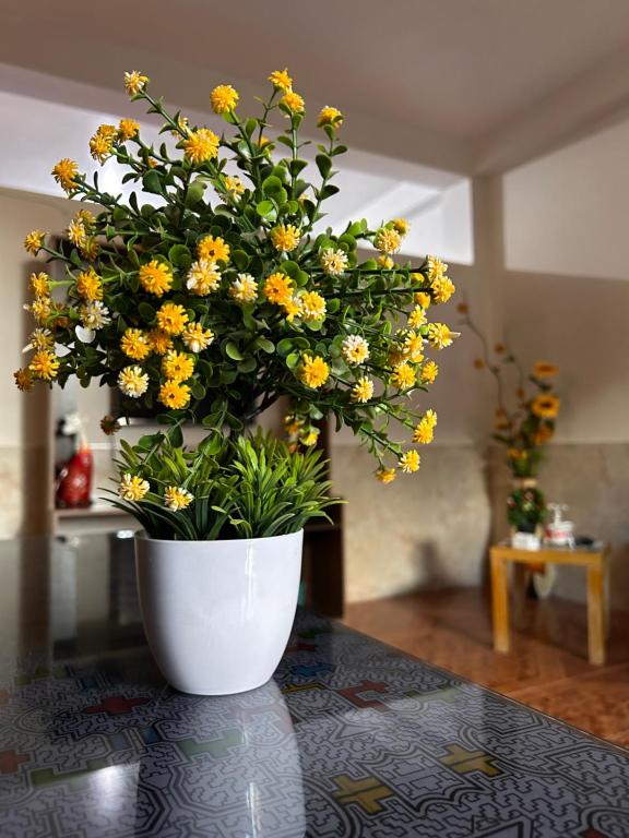 普卡尔帕ALAMEDAS APARMENTs的白色的花瓶,上面有黄色的花朵