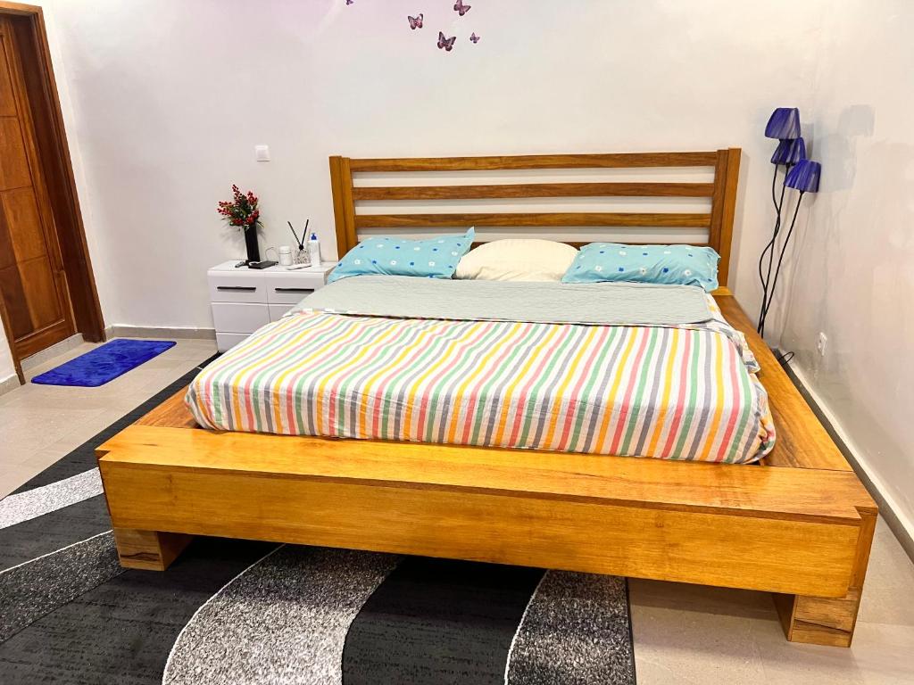 达喀尔LUXE Studio的一间卧室配有一张带蓝色枕头的木床。