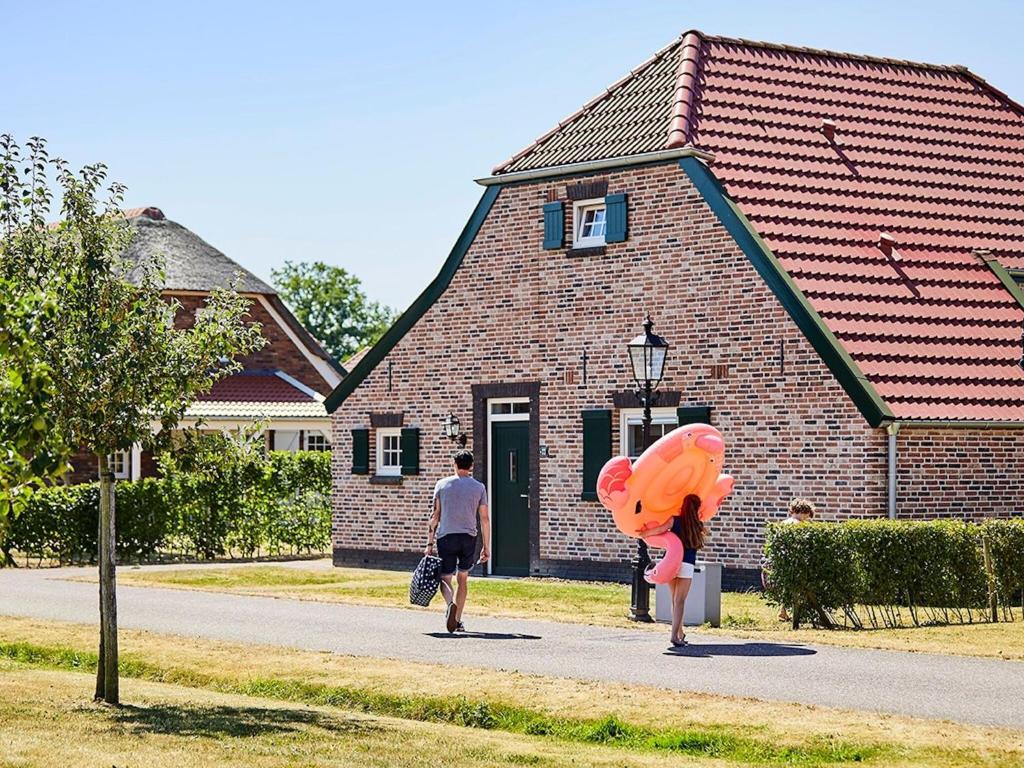 罗赫尔Nice farmhouse villa with PlayStation, in Limburg的两个人在大楼前的街道上走
