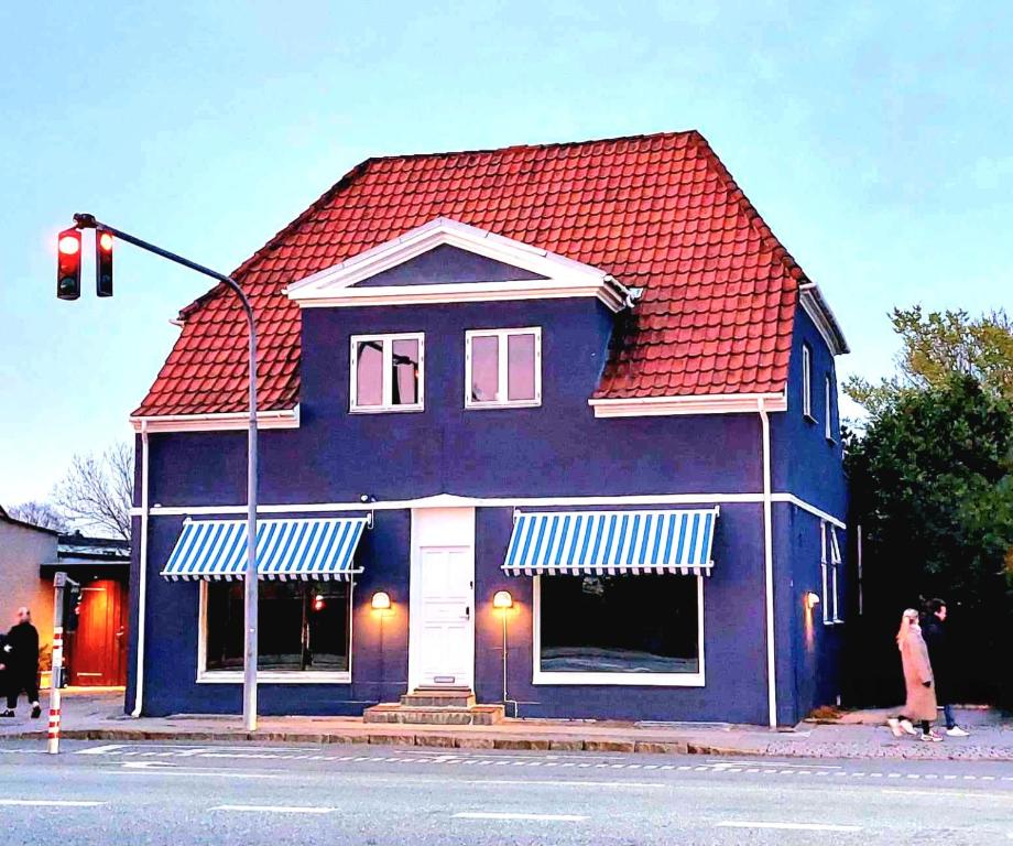 哥本哈根Guesthouse 'Blue House' in vintage villa&garden的街上有红色屋顶的蓝色房子