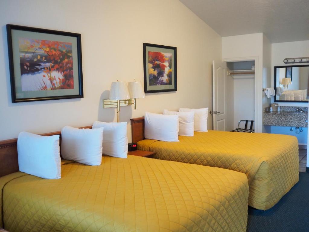 布鲁金斯野河汽车旅馆的配有黄色床单的酒店客房的两张床