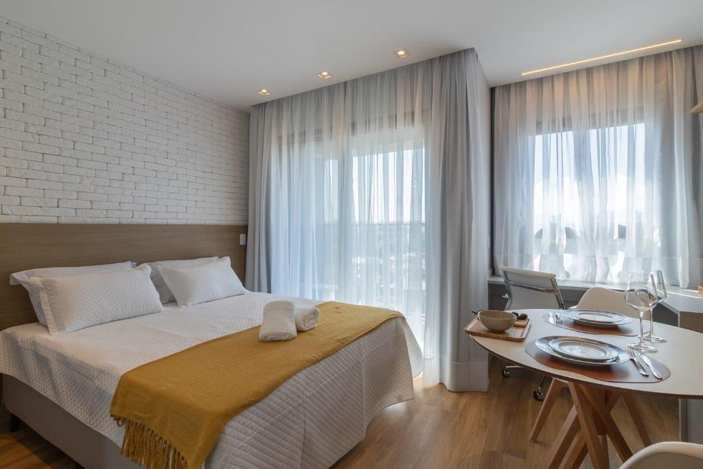圣保罗Studio Campo Belo II的酒店客房设有一张床铺、一张桌子和一间用餐室。