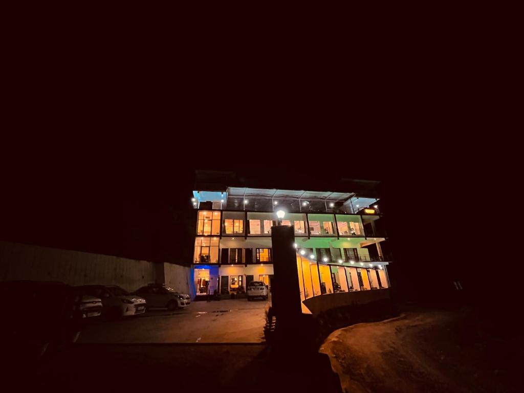 朱纳格特Siluswar Hotel的夜间有灯的建筑,有停车位