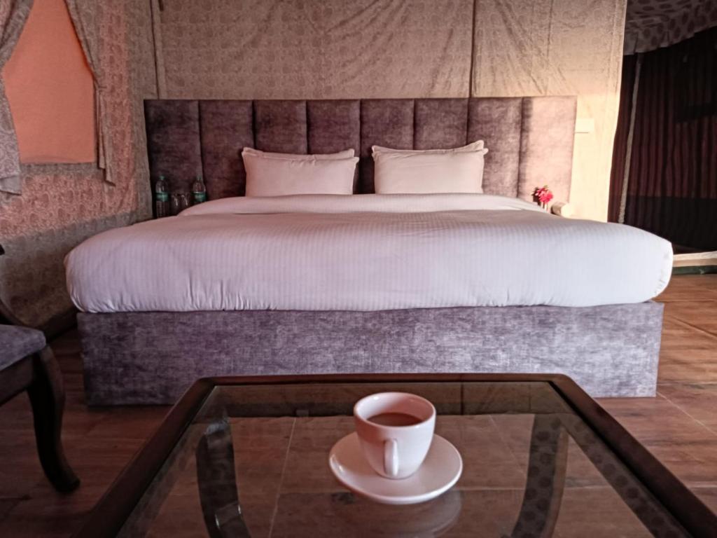 萨哈兰普尔Pulastya Wellness Resort的卧室配有一张床,餐桌上备有咖啡
