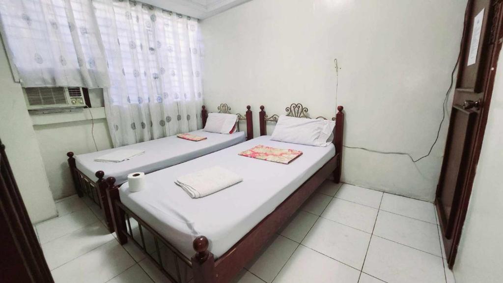 宿务Goland Pension House & Dormitory by SMS Hospitality的带窗户的客房内设有两张单人床。