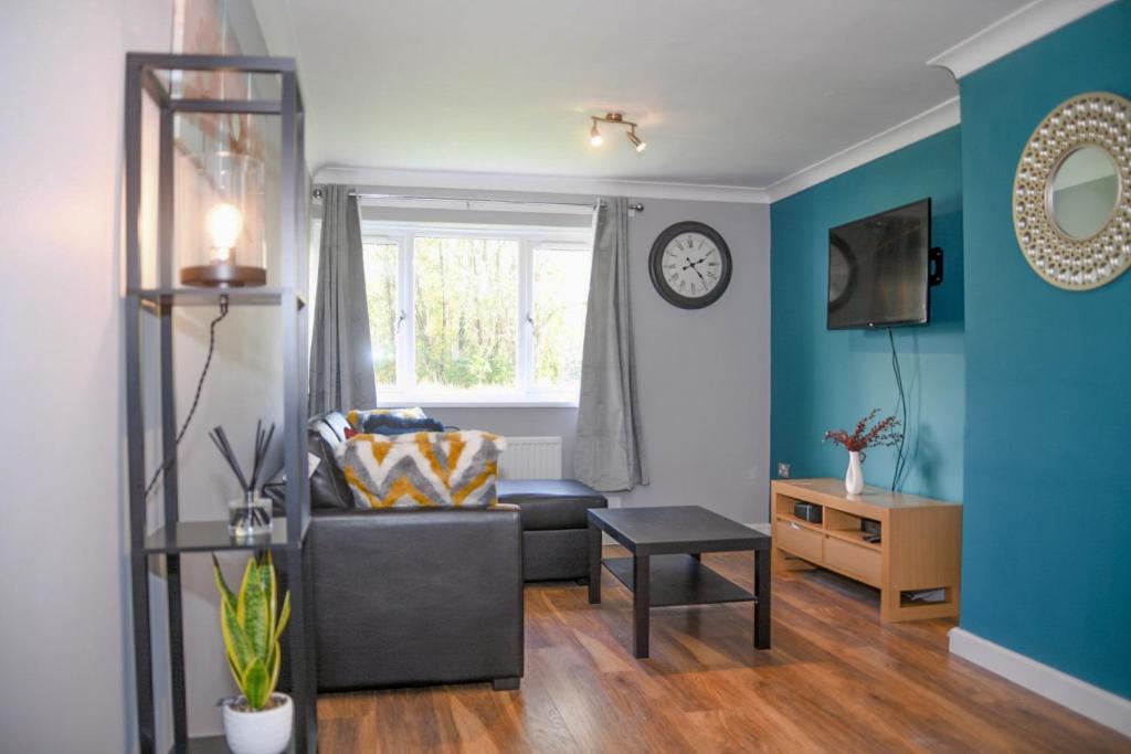 Willenhall2ndHomeStays- Willenhall-A Serene 3 Bed House with a Garden View-Suitable for Contractors and Families-Sleeps 9 - 7 mins to J10 M6 and 21 mins to Birmingham的客厅配有沙发和墙上的时钟
