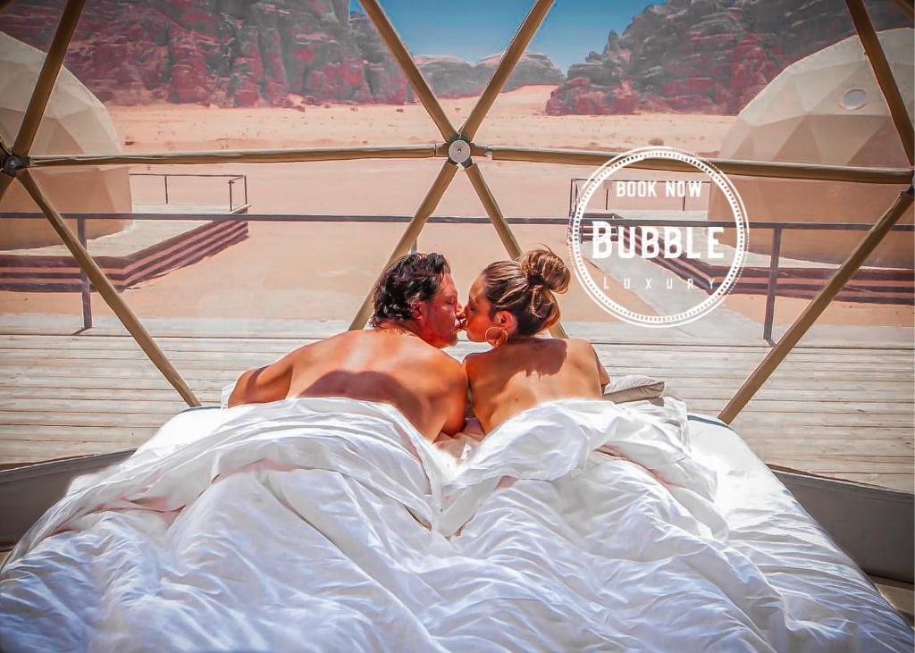 瓦迪拉姆Wadi rum Bubble luxury camp的躺在床上的男人和女人