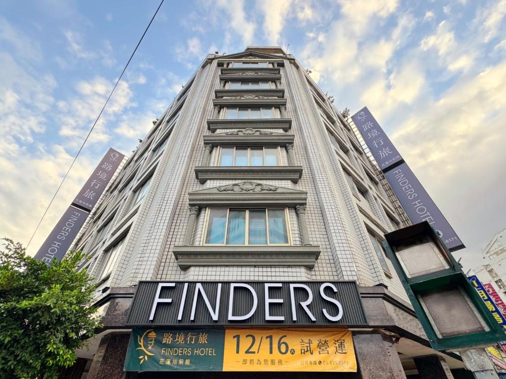 花莲市Finders Hotel Hualien Station的一座高大的建筑,旁边有一个标志