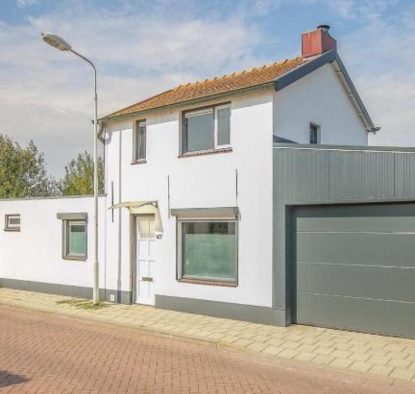 韦斯特多珀Leuk vakantiewoning dijk woning met 3 slaapkamers dicht bij de Belgische grensen的街上的白色房子,带车库