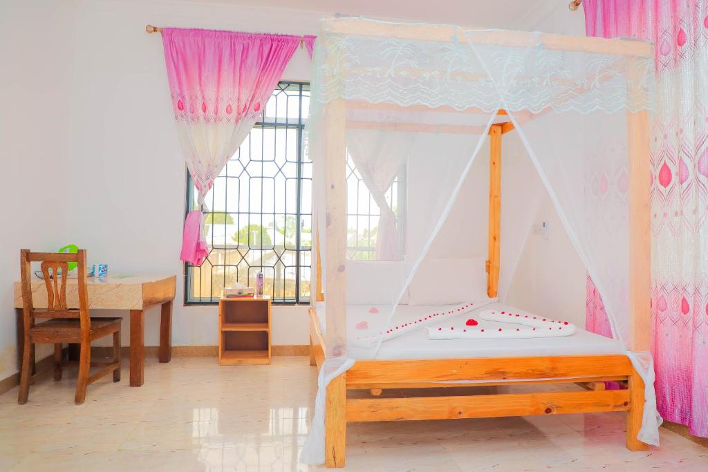 南威Raha house的一间卧室配有一张床、一张书桌和一个窗户。