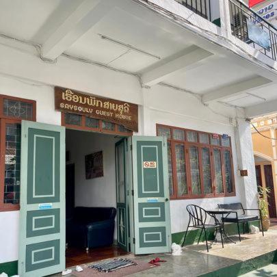 Ban NongdouangSaysouly Guest House的一座带绿门、桌子和椅子的建筑