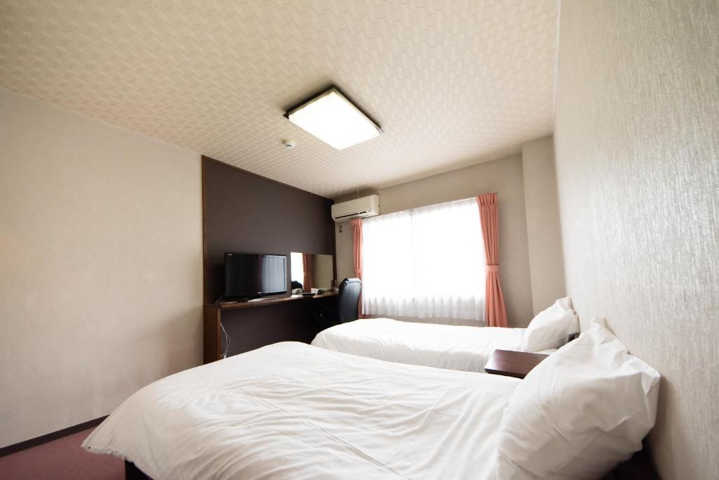 奈良Yamato Saidaiji Hotel SINDAI的酒店客房设有两张床和窗户。