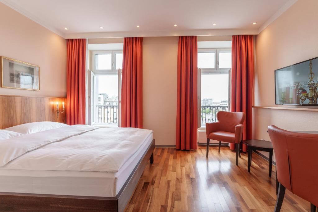 巴塞尔巴塞尔施维瑟酒店的卧室配有白色大床和红色窗帘