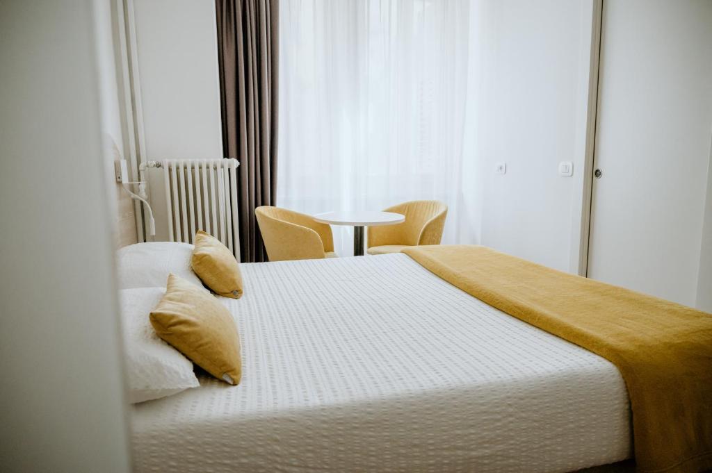 特伦托威尼斯酒店的一间卧室设有两张床、一张桌子和一个窗口