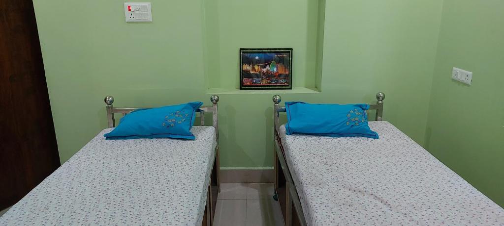 德奥加尔Anand Bhavan的医院客房的两张床,配有蓝色枕头