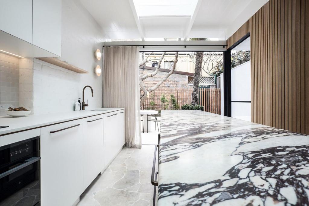 悉尼The Timeless Modern Glebe的厨房配有白色橱柜和大理石台面