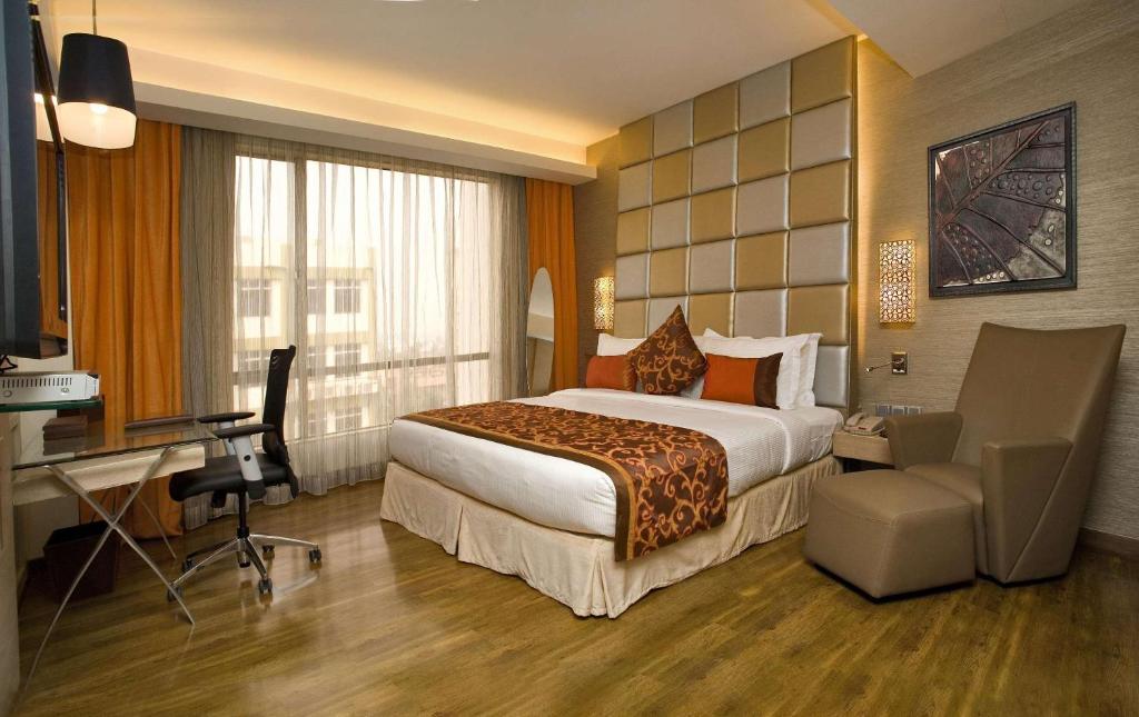 新德里Hotel Park Seven Near Delhi International Airport的配有一张床和一张书桌的酒店客房