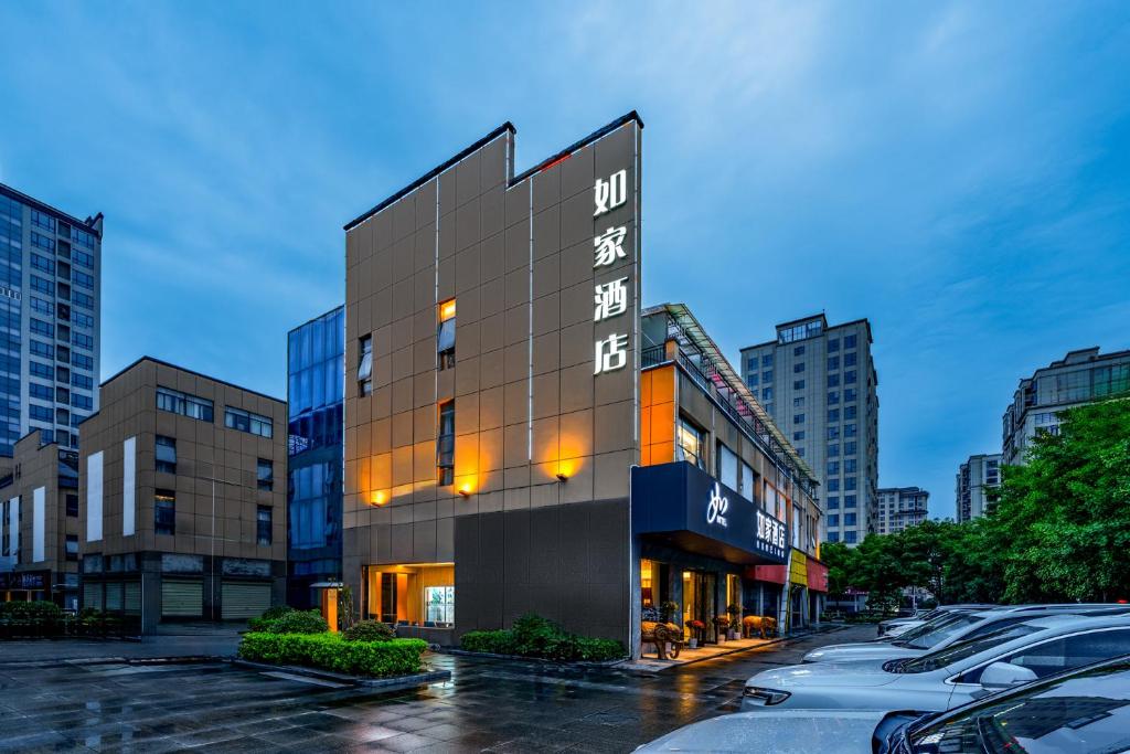 张家界Home Inn Zhangjiajie Tianmen Mountain Branch的城市街道上的一座建筑物,有车辆停放