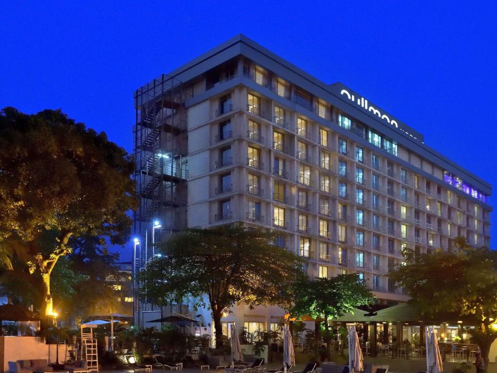金沙萨金沙萨格兰德铂尔曼酒店的一座高大的建筑,晚上有很多窗户