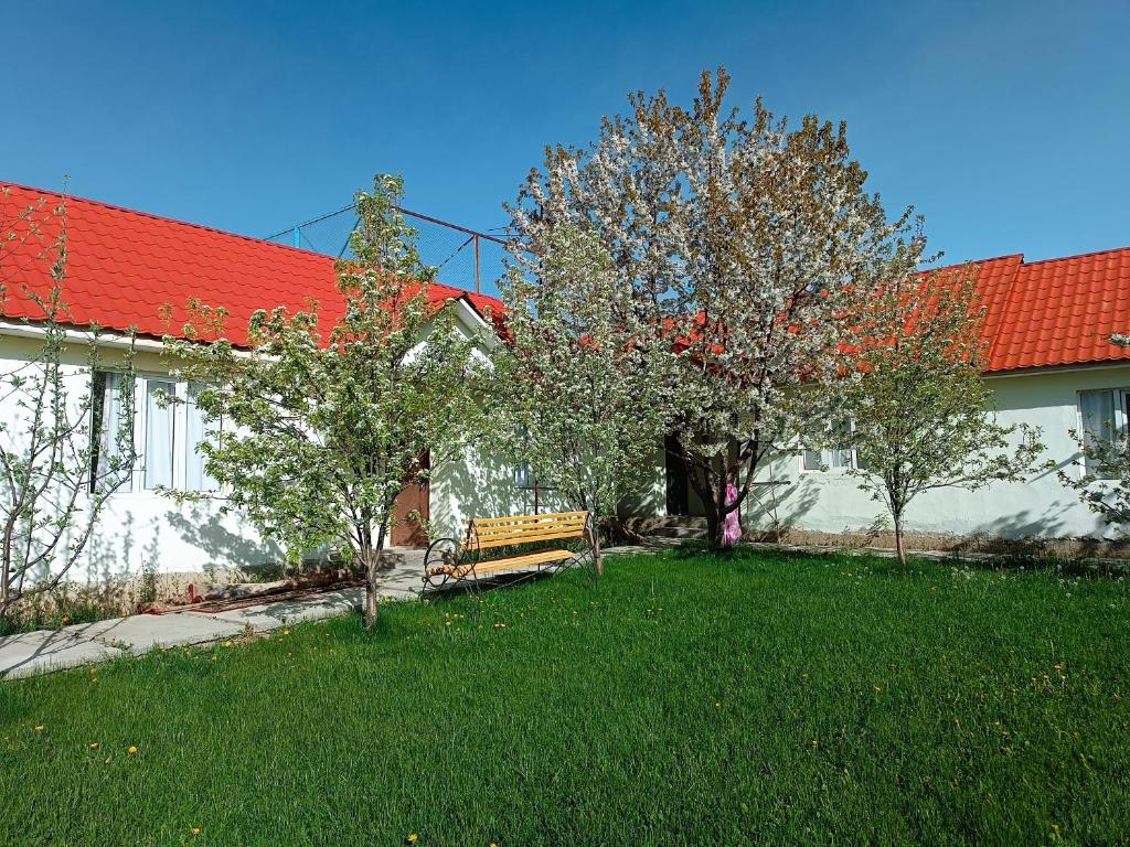 乔尔蓬阿塔Гостевой дом ТОЛНУР的一座建筑前的庭院,里面种着树木,设有长凳
