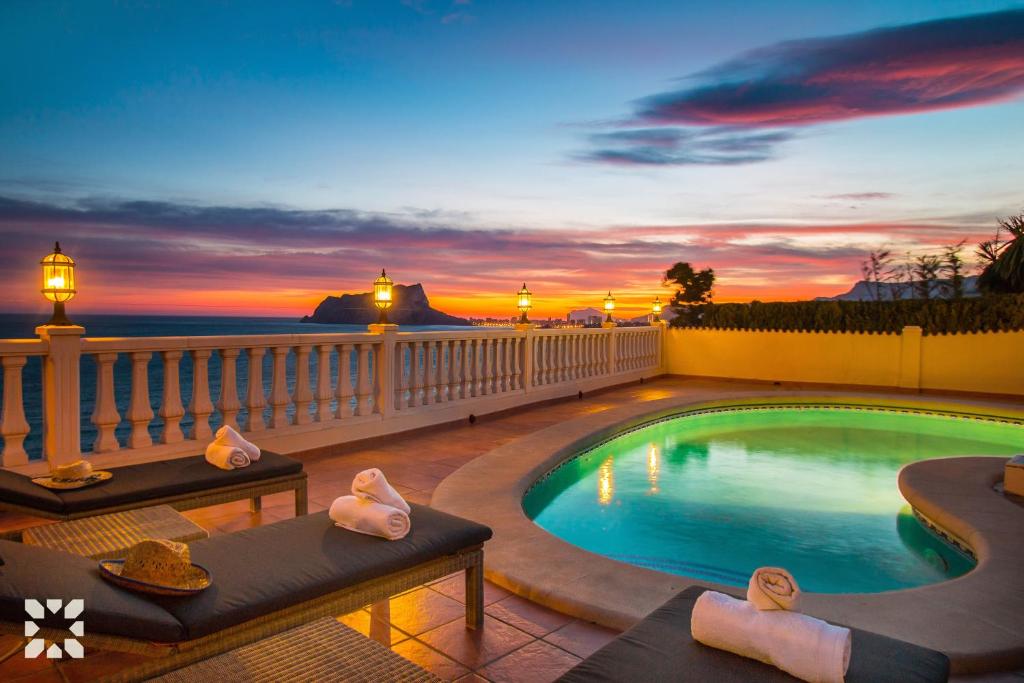 特乌拉达Villa Blue Sea by Abahana Villas的一个带2张躺椅的游泳池,享有日落美景